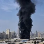 Composite news graphic showing explosions over the skylines of Dubai, Abu Dhabi, and Doha, with missile interceptions lighting up the night sky and air raid sirens sounding in Tel Aviv during escalating Middle East conflict.