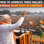 Prime Minister Narendra Modi speaking at a huge BJP rally in West Bengal, waving to a large crowd with party flags during election campaign.