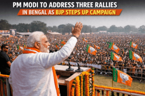 Prime Minister Narendra Modi speaking at a huge BJP rally in West Bengal, waving to a large crowd with party flags during election campaign.